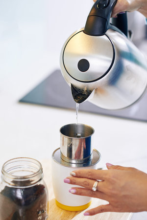 Close-up image of woman pouring hot water on ground coffee in drip filterの写真素材