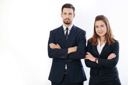 Studio portrait of smiling confident businessman and businesswoman standing with arms foldedの写真素材