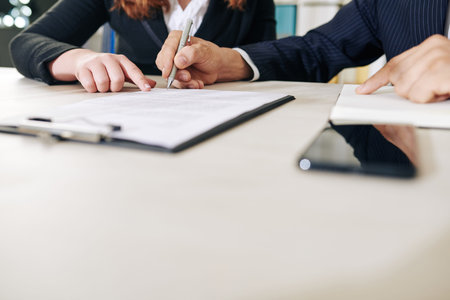 Businesswoman pointing at financial document when asking colleague to sing it