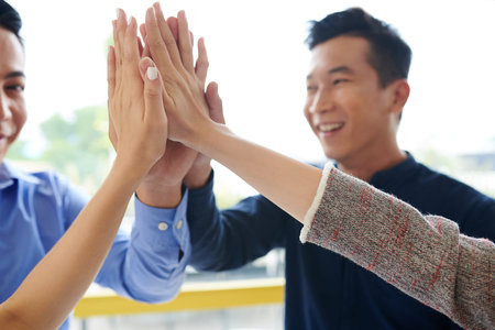 Close-up image of business people giving high five after finishing work on big project