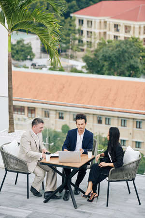 Business team having meeting at table on rooftop of office buildingの写真素材