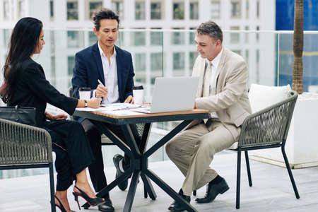 Serious confident business people discussing financial charts and reports and planning work at meetingの写真素材