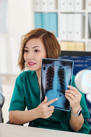 Radiologist making video call and pointing at dark spot on chest x-ray of patient