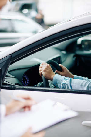 Man sitting in new car in dealership with hands on steering wheelの写真素材
