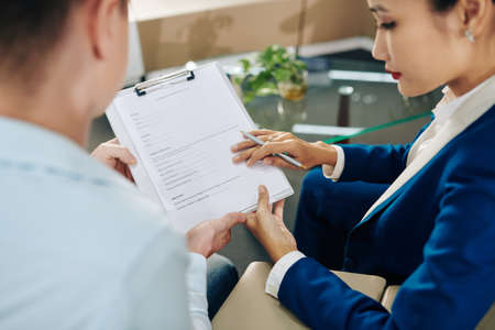 Dealership manager helping customer to fill information in vehicle purchase agreementの写真素材