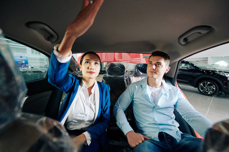 Car dealership manager showing customer how to turn on light in automobile compartment