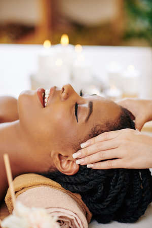 Close-up image of young Black pretty woman getting face and head massage in spa salonの写真素材