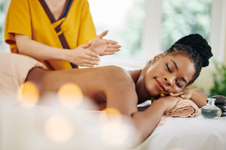 Happy charming young Black woman keeping her eyes closed when enjoying back massage