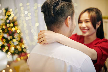 Hugging young Asian couple in love celebrating Christmas at homeの写真素材