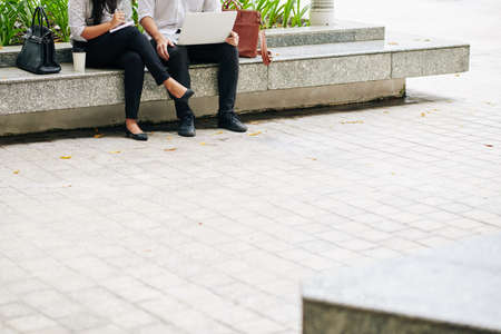 Cropped image of business people sitting outdoors, working on laptop and planning future projectsの写真素材