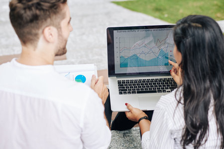 Business people analyzing charts and diagrams on screen of laptop at meeting
