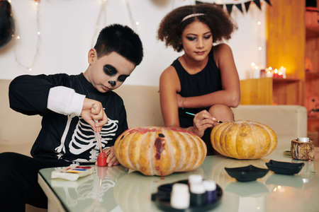 Children painting carved pumpkins for Halloween celebrationの写真素材