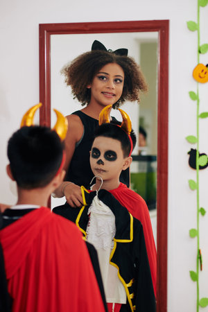 Elder sister helping preteen boy to choose costume for Halloween party