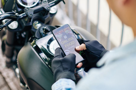 Close-up image of motorcyclist ordering food via mobile applicationの写真素材