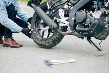 Close-up image of man replacing damaged tire of motorcycleの写真素材