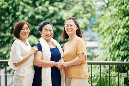 Group of happy smiling female friends standing on balcony and looking at cameraの写真素材