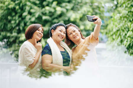 Group of happy senior female friends taking selfie when standing outdoorの写真素材