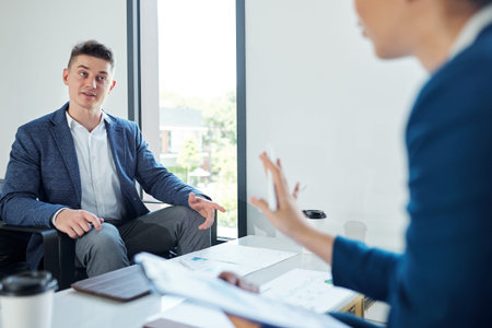 Young handsome entrepreneur talking to colleague at meeting