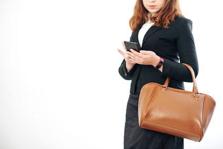 Cropped image of confident young businesswoman checking text messages in smartphone, isolated on...