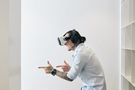 Cheerful young man in virtual reality headset playing action shooter