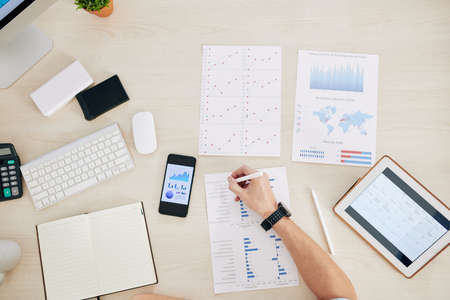Entrepreneur analyzing documents with charts and reports at office table, view from the topの写真素材