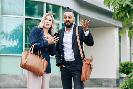 Multi-ethnic business people standing outdoors and trying to catch taxi