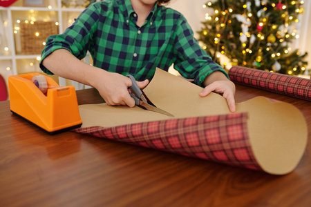 Teenage boy cutting wrapping paper