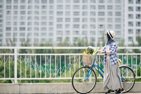 Woman with bicycle standing on bridgeの写真素材