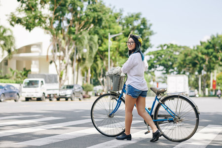Woman with bicycle crossing roadの写真素材