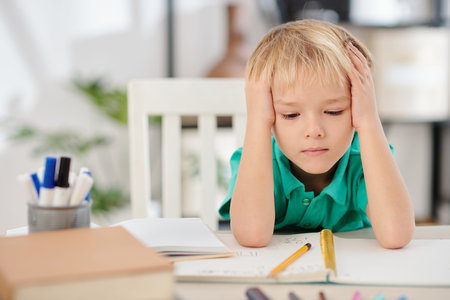 Schoolboy looking at opened textbook