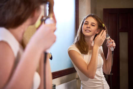 Teenage girl curling hairの写真素材