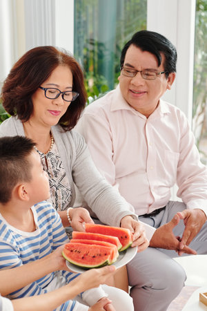 Offering watermelon slices to grandparents