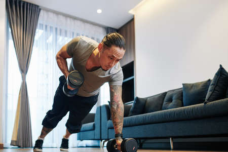 Man doing dumbbells plank row exerciseの写真素材