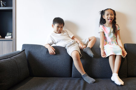 Cheerful siblings sitting on sofa