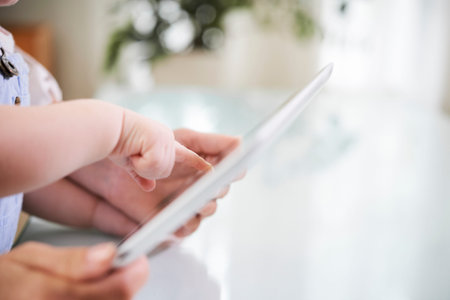 Close-up image of mother and little boy pointing at tablet computer with application on screen