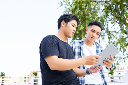 Two Asian teenagers using digital tablet together in the city