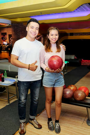 Portrait of Asian young couple smiling at camera while playing bowlingの写真素材