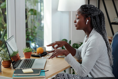Pretty young female entrepreneur with braided hair explaining her point of view when talking at...