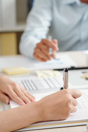 Close-up image of businesswoman or lawyer proofreading contract and correcting important details