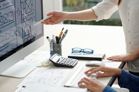 Project manager and ux designer discussing layout of new website page on computer screen