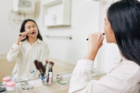 Young woman looking at bathroom window when brushing teeth in the morningの写真素材
