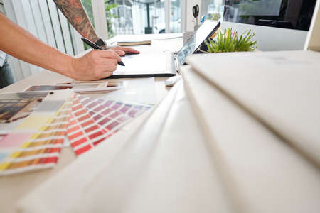 Hands of graphic designer drawing on tablet computer with digital pen when working sketches for projectの写真素材