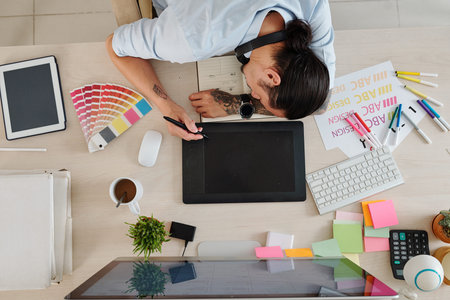 Graphic designer fell asleep when drawing on graphic tablet with digital pen, view from above