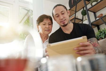Smiling mature mixed-race man showing new helpful application on tablet computer to his mature...