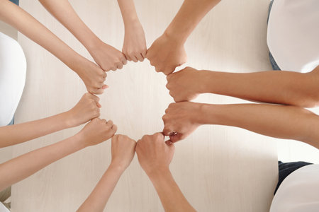 Hands of volunteers of charity center making circle with clenched fists, expressing support and unityの写真素材