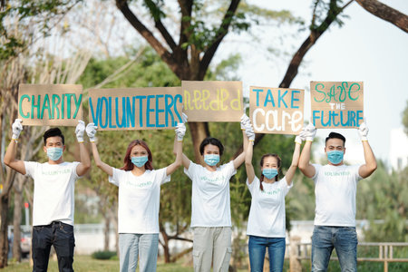 Team of young Asian volunteers raising placards over heads when promoting charity organizationの写真素材
