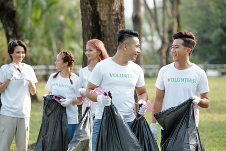 Young men and women picking up trash when cleaning city parkの写真素材