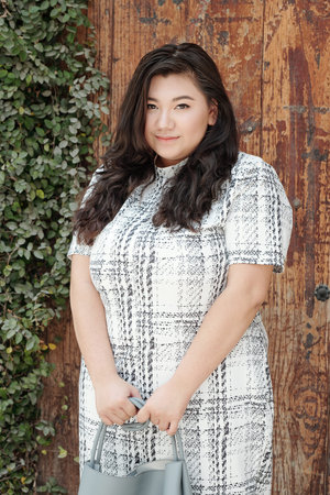 Portrait of young attractive plus size woman standing oudoors with leather bag in her hands and...