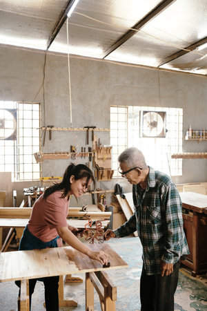 Smilinf young woman covering sanded wood board with oil to retain its natural properties, like breathing, remaining flexible, and creating a better textureの写真素材