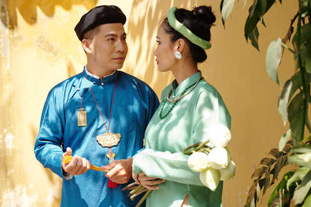 Newly married Vietnamese man and woman in traditional costumes looking at each otherの写真素材